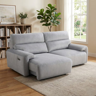 grey electric sliding sofa in a living room with a bookshelf and plants.