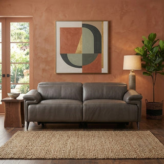 grey leather electric recliner sofa in a living room with a abstract painting on the wall and a plant.