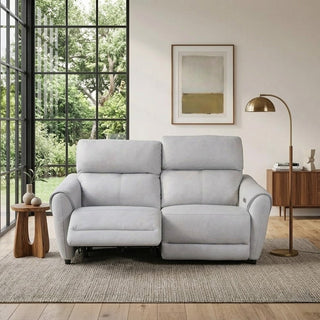 grey recliner sofa in a living room with large windows and a lamp.
