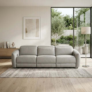 grey sofa in a modern living room with large windows and plants.