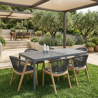 sintered stone outdoor table and chairs on a grassy lawn, surrounded by plants and trees.