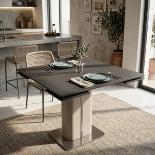square extendable dining table with plates, cutlery, and a vase in a modern kitchen.
