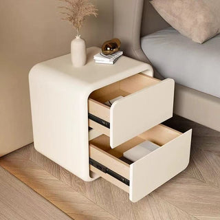 white bedside table with open drawer next to a bed in a bedroom setting