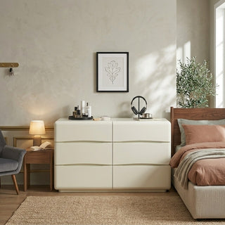 white chest of drawers in a bedroom with a bed, lamp, and wall art.