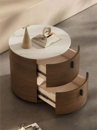 wooden round bedside table with marble top and open drawer on a neutral background